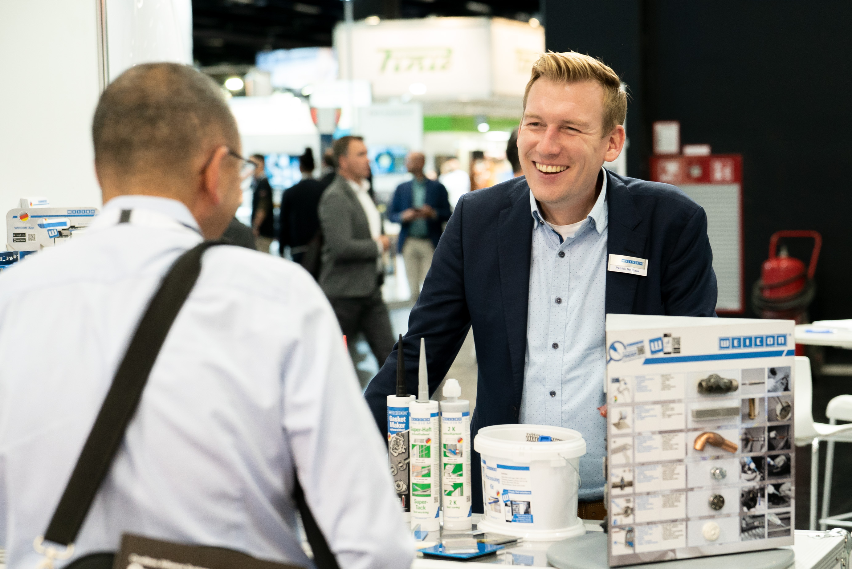 2 Männer stehen am Messestand von Weicon und unterhalten sich