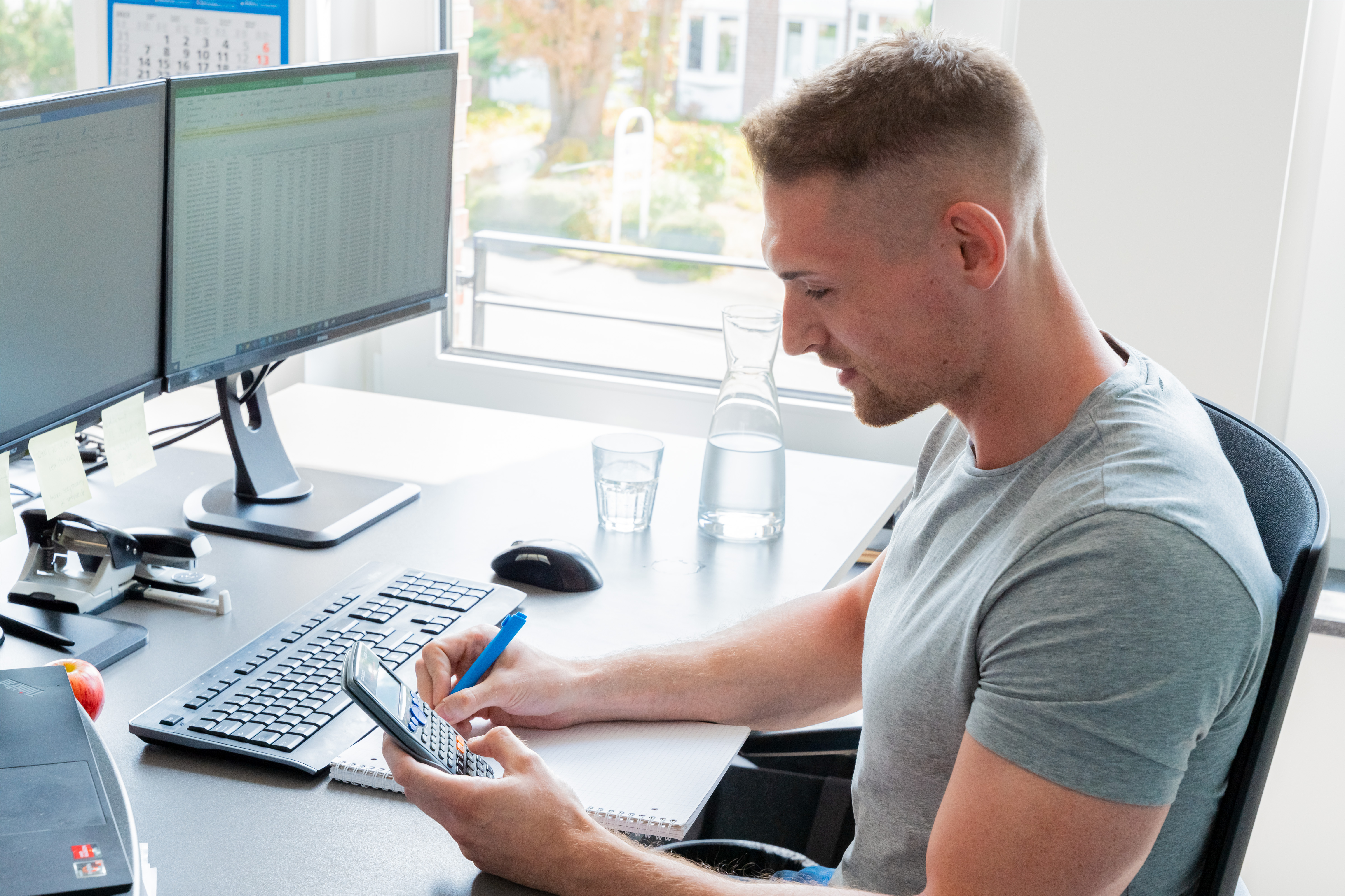 Ein Mann sitzt im Büro am Schreibtisch und tippt etwas in den Taschenrechner