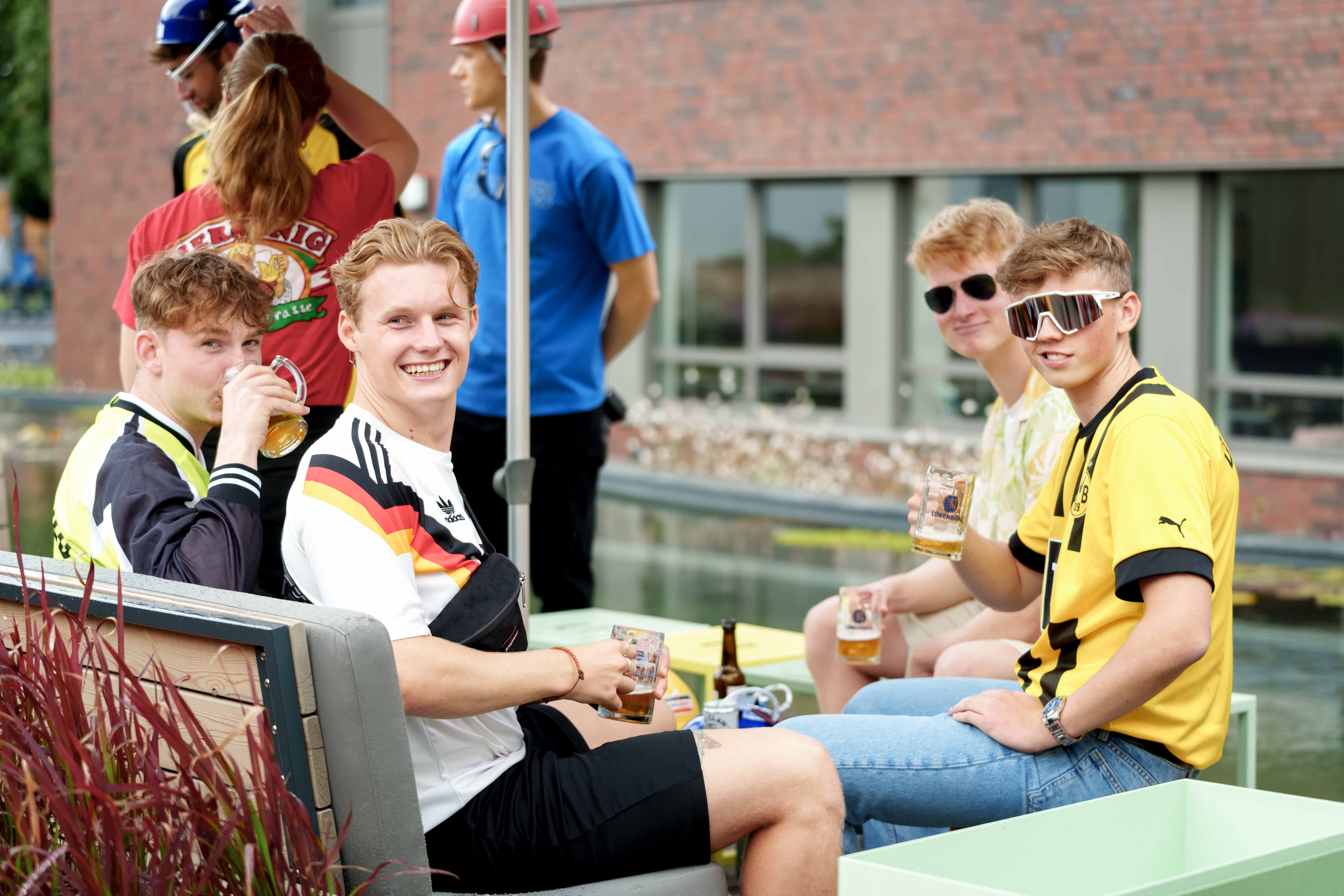 Eine Gruppe von Jungs sitzt mit Fußballtrikots und Sonnenbrille am Pool